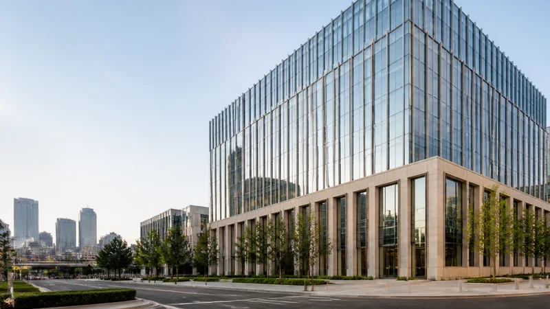 Wide establishing view of a downtown office tower, soft daylight, clear open sky for overlaid text