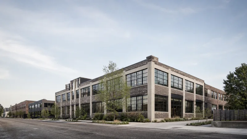 Wide establishing view of a creative studio loft building, soft daylight, clear open sky for overlaid text