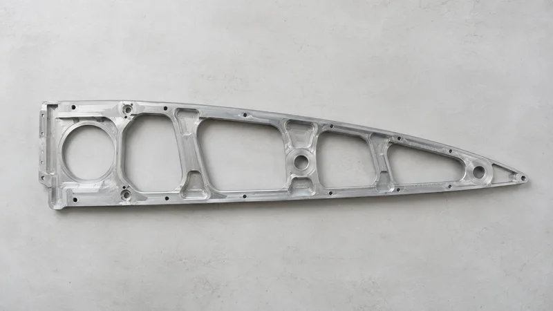 Styled flat-lay of a machined aluminium aircraft wing rib on a clean background, clean even studio light, generous negative space for overlaid text