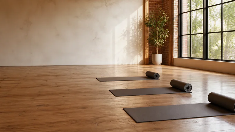 Wide interior view of a open wood-floor studio with rolled mats with no people, bright daylight through the windows, clean uncluttered foreground for text