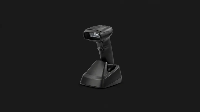 Isolated a cordless barcode scanner in a charging cradle centred on a seamless deep charcoal near-black studio background, generous empty margin on every side for overlaid branding