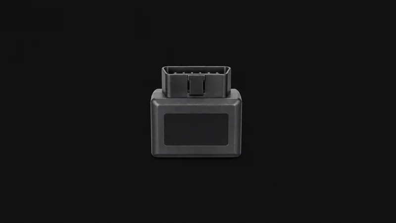 Isolated a plug-in vehicle telematics dongle with a blank status window centred on a seamless deep charcoal near-black studio background, generous empty margin on every side for overlaid branding