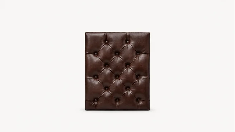 Isolated a deep-buttoned leather panel with tufted diamonds centred on a seamless pale off-white studio background, generous empty margin on every side for overlaid branding