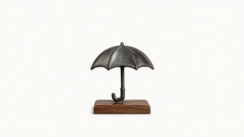 Isolated a cast-metal umbrella emblem on a wooden base centred on a seamless pale off-white studio background, generous empty margin on every side for overlaid branding
