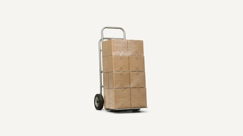 Isolated a stack of stretch-wrapped removal cartons on a hand truck centred on a seamless pale off-white studio background, generous empty margin on every side for overlaid branding