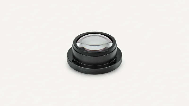 Isolated a polished aspheric lens element in a black anodised mount centred on a seamless pale off-white studio background, generous empty margin on every side for overlaid branding