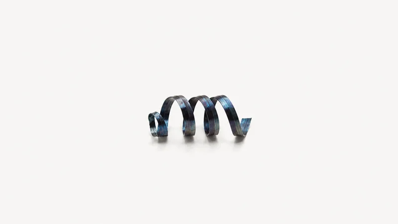 Isolated a ribbon of blue-tinted steel swarf coiled into a spring centred on a seamless pale off-white studio background, generous empty margin on every side for overlaid branding