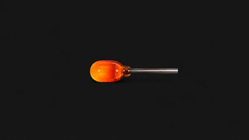 Isolated a gather of molten glass glowing on the end of a steel blowpipe centred on a seamless deep charcoal near-black studio background, generous empty margin on every side for overlaid branding