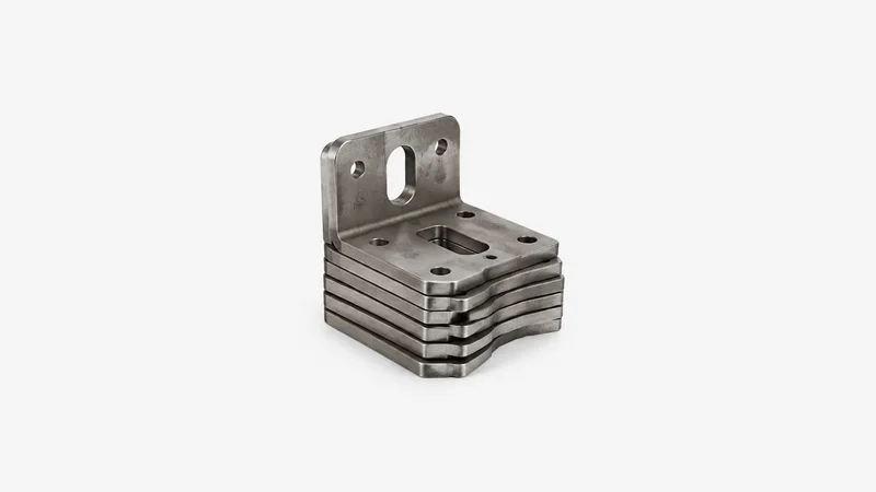 Isolated a stack of laser-cut mild-steel brackets with clean burr-free edges centred on a seamless pale off-white studio background, generous empty margin on every side for overlaid branding
