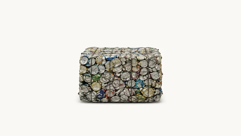 Isolated a compressed bale of crushed aluminium drink cans centred on a seamless pale off-white studio background, generous empty margin on every side for overlaid branding