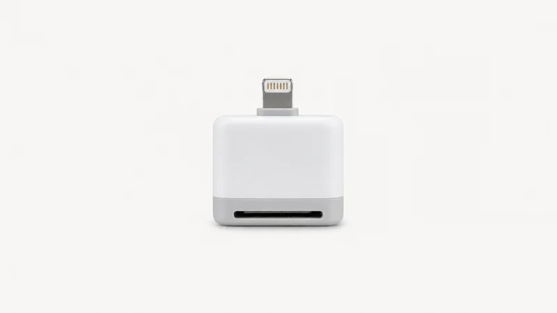 Isolated a compact card-reader dongle with a lightning connector centred on a seamless pale off-white studio background, generous empty margin on every side for overlaid branding