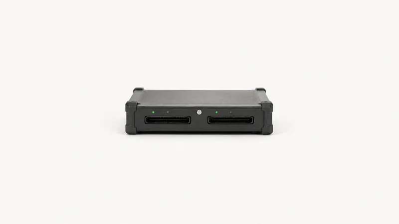 Isolated a forensic write-blocker with twin drive ports centred on a seamless pale off-white studio background, generous empty margin on every side for overlaid branding