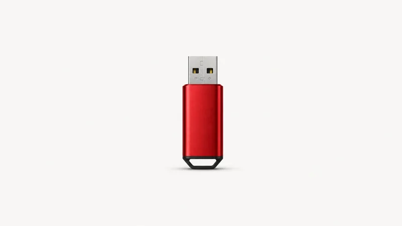 Isolated a USB boot drive with a red anodised shell centred on a seamless pale off-white studio background, generous empty margin on every side for overlaid branding
