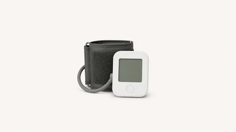 Isolated a bluetooth upper-arm blood-pressure cuff with a blank display unit centred on a seamless pale off-white studio background, generous empty margin on every side for overlaid branding