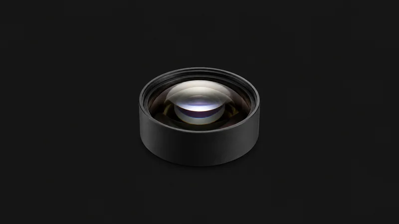 Isolated a polished aspheric lens element in a black anodised mount centred on a seamless deep charcoal near-black studio background, generous empty margin on every side for overlaid branding