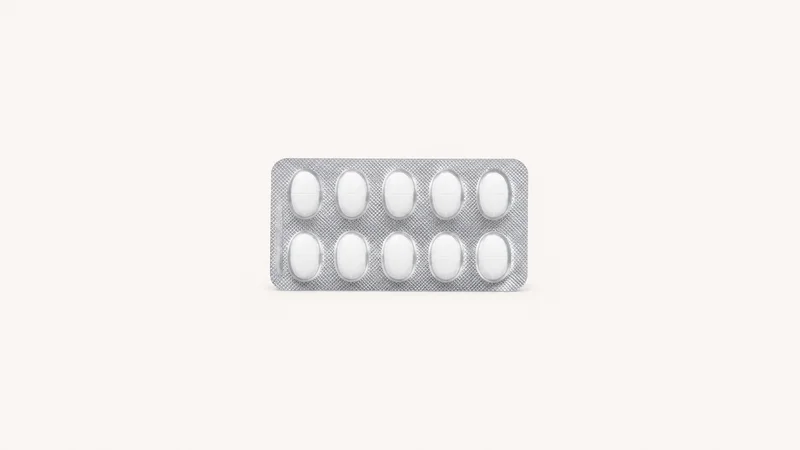 Isolated a blister pack of white oval tablets with foil backing centred on a seamless pale off-white studio background, generous empty margin on every side for overlaid branding