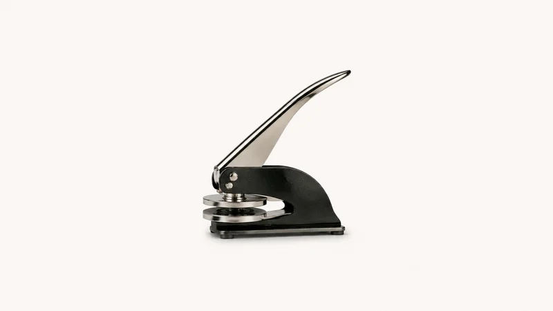 Isolated an embossing seal press with a long lever centred on a seamless pale off-white studio background, generous empty margin on every side for overlaid branding