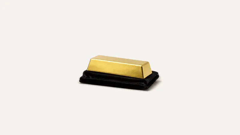 Isolated a gold-plated ingot resting on a black velvet cloth centred on a seamless pale off-white studio background, generous empty margin on every side for overlaid branding