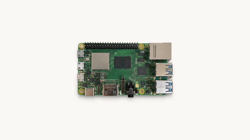 Isolated a single-board computer with exposed GPIO header pins centred on a seamless pale off-white studio background, generous empty margin on every side for overlaid branding