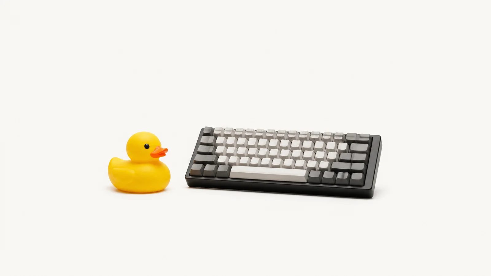 Isolated a rubber duck sitting beside a mechanical keyboard centred on a seamless pale off-white studio background, generous empty margin on every side for overlaid branding