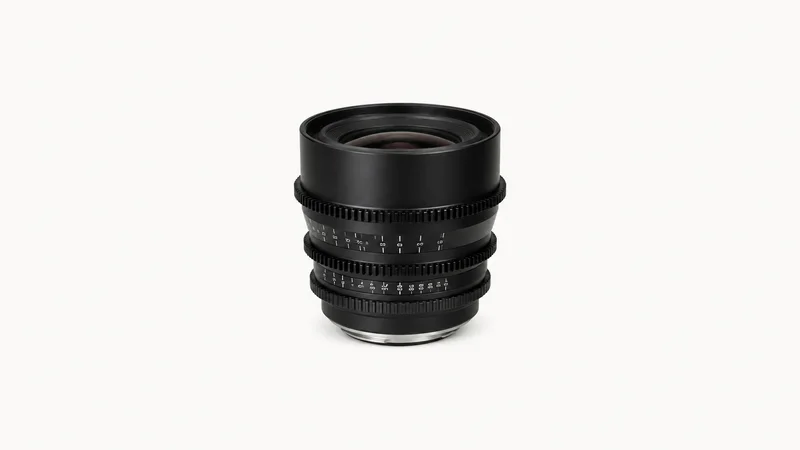 Isolated a cine prime lens with geared focus rings centred on a seamless pale off-white studio background, generous empty margin on every side for overlaid branding
