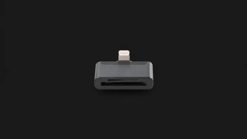 Isolated a compact card-reader dongle with a lightning connector centred on a seamless deep charcoal near-black studio background, generous empty margin on every side for overlaid branding
