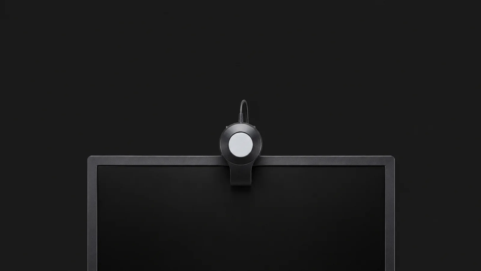 Isolated a colour-calibration puck resting on a monitor edge centred on a seamless deep charcoal near-black studio background, generous empty margin on every side for overlaid branding