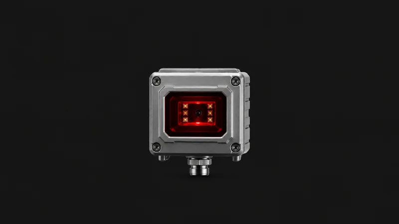 Isolated a fixed-mount industrial barcode reader in a metal housing with a red aperture centred on a seamless deep charcoal near-black studio background, generous empty margin on every side for overlaid branding