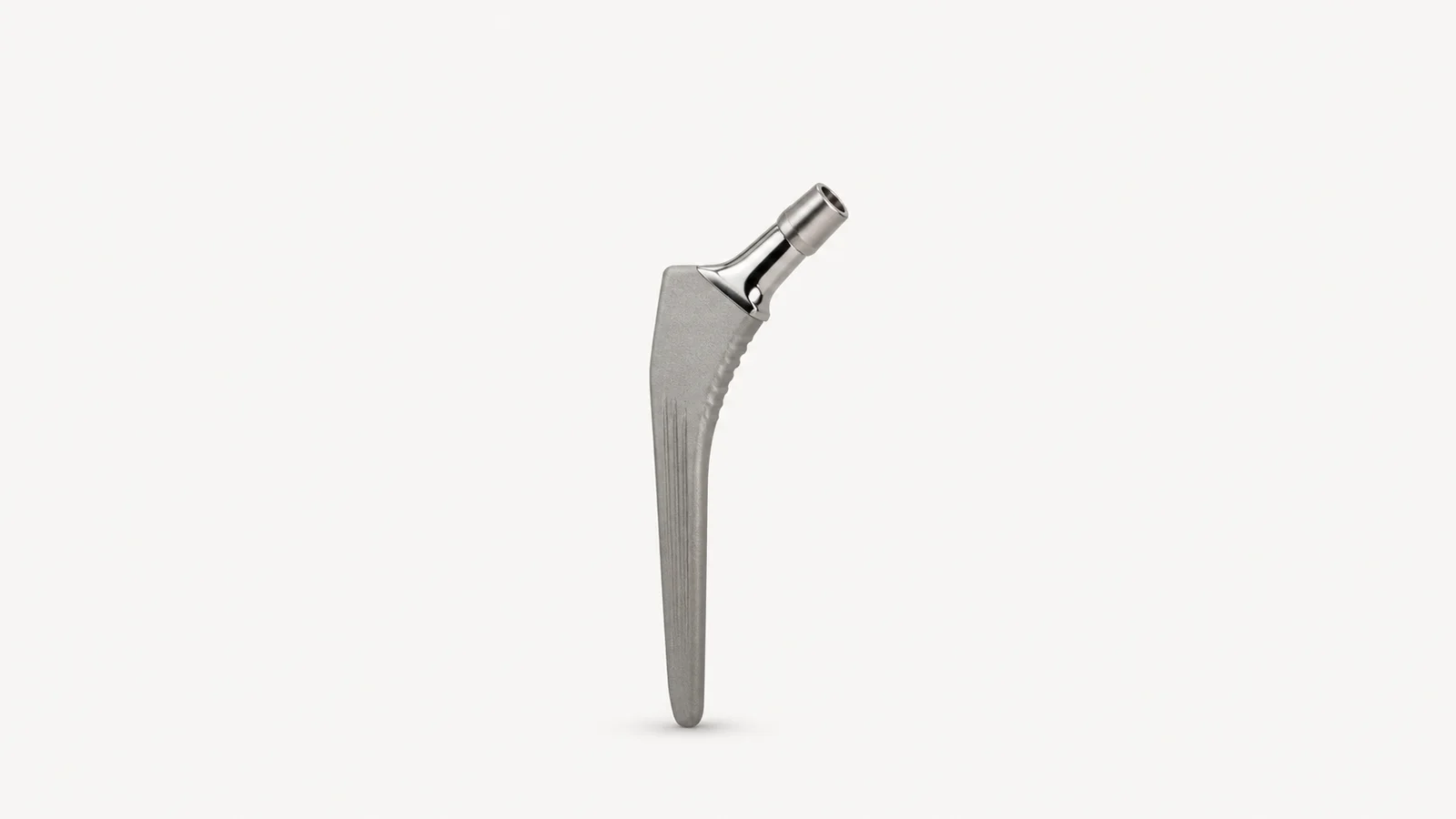 Isolated a titanium hip-stem implant with a polished neck centred on a seamless pale off-white studio background, generous empty margin on every side for overlaid branding