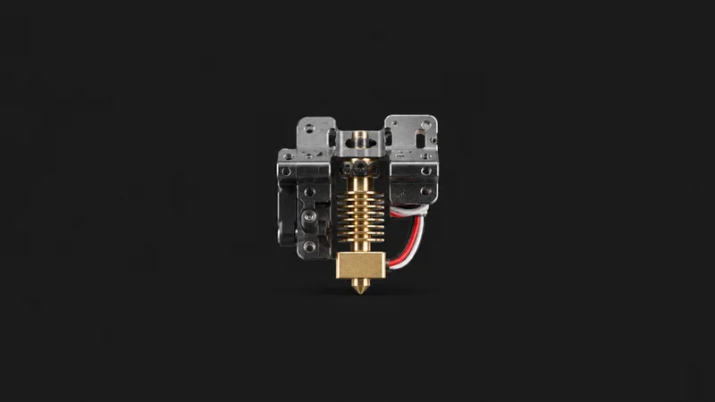 Isolated a brass hot-end nozzle and heater block on a bare extruder carriage centred on a seamless deep charcoal near-black studio background, generous empty margin on every side for overlaid branding