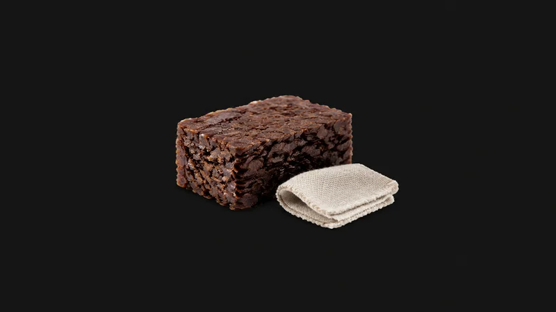 Isolated a block of dark shellac flakes beside a rubbing pad centred on a seamless deep charcoal near-black studio background, generous empty margin on every side for overlaid branding