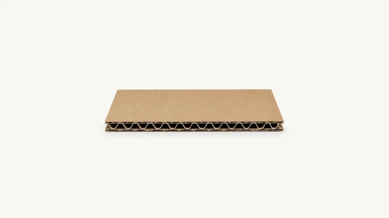 Isolated a single-wall corrugated board sample showing the fluted core centred on a seamless pale off-white studio background, generous empty margin on every side for overlaid branding