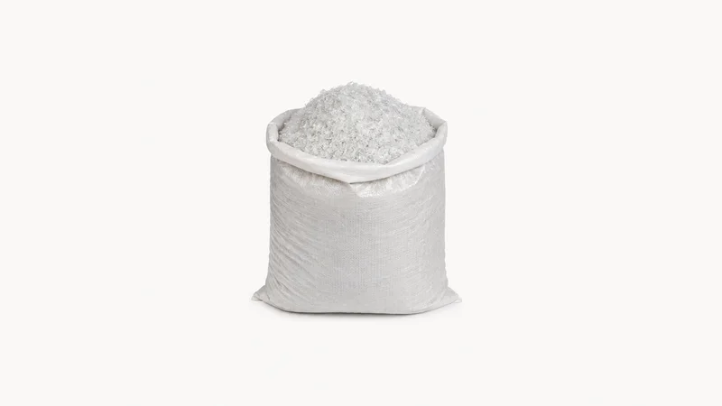 Isolated a sack of washed clear PET flakes centred on a seamless pale off-white studio background, generous empty margin on every side for overlaid branding