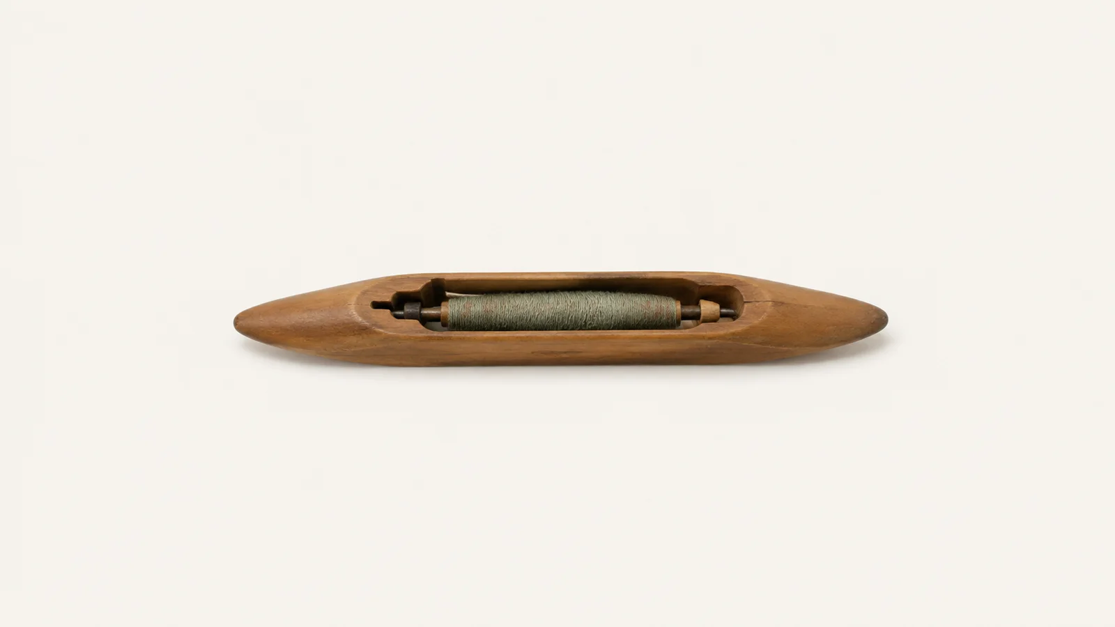 Isolated a wooden weaving shuttle with a pirn of yarn centred on a seamless pale off-white studio background, generous empty margin on every side for overlaid branding