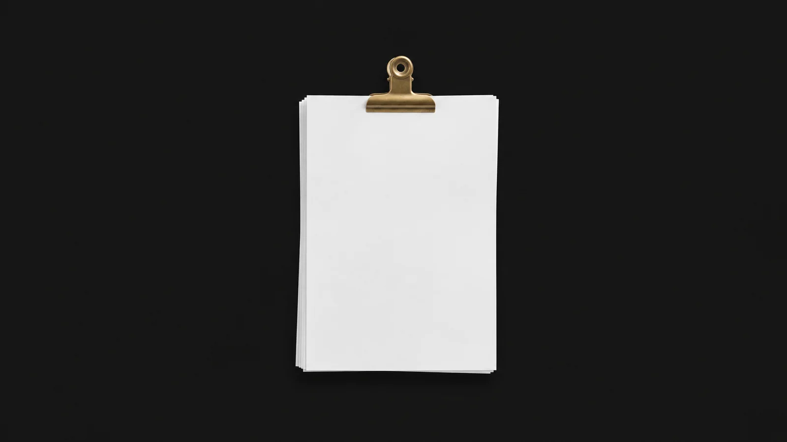 Isolated a stack of blank cv sheets clipped with a brass bulldog clip centred on a seamless deep charcoal near-black studio background, generous empty margin on every side for overlaid branding
