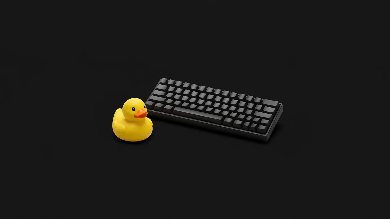 Isolated a rubber duck sitting beside a mechanical keyboard centred on a seamless deep charcoal near-black studio background, generous empty margin on every side for overlaid branding