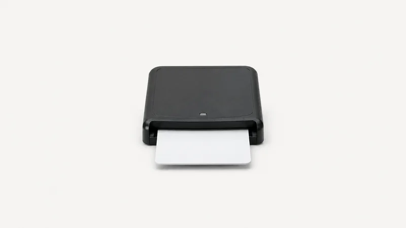 Isolated a smart card reader with a half-inserted blank card centred on a seamless pale off-white studio background, generous empty margin on every side for overlaid branding