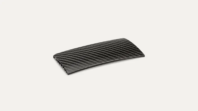 Isolated a carbon-fibre wing-skin coupon with a visible weave centred on a seamless pale off-white studio background, generous empty margin on every side for overlaid branding