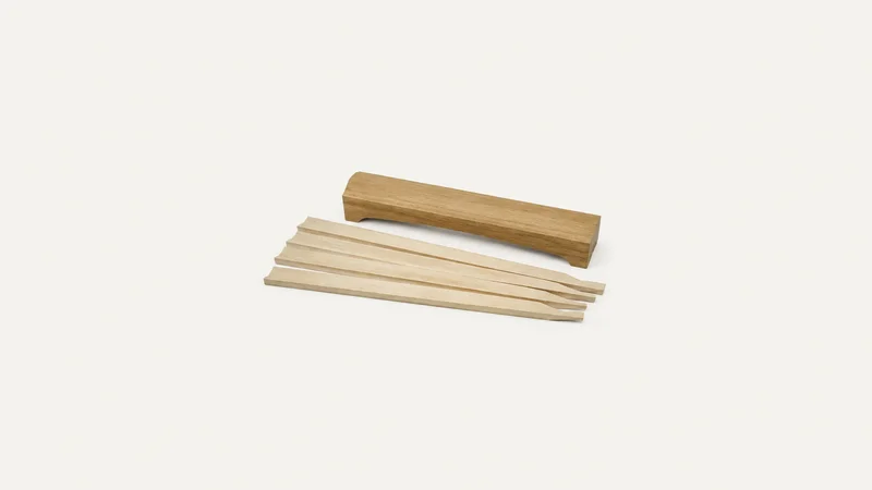 Isolated a set of loose spruce brace bars laid beside a wooden go-bar centred on a seamless pale off-white studio background, generous empty margin on every side for overlaid branding