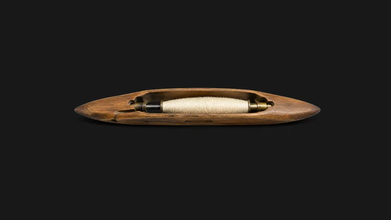 Isolated a wooden weaving shuttle with a pirn of yarn centred on a seamless deep charcoal near-black studio background, generous empty margin on every side for overlaid branding