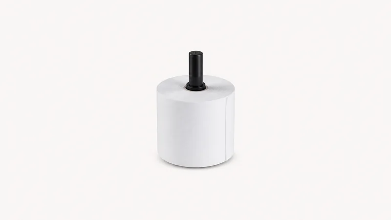 Isolated a roll of blank till receipts on a spindle centred on a seamless pale off-white studio background, generous empty margin on every side for overlaid branding