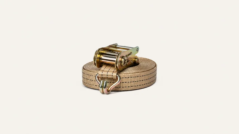 Isolated a ratchet tie-down strap coiled with its metal hook centred on a seamless pale off-white studio background, generous empty margin on every side for overlaid branding
