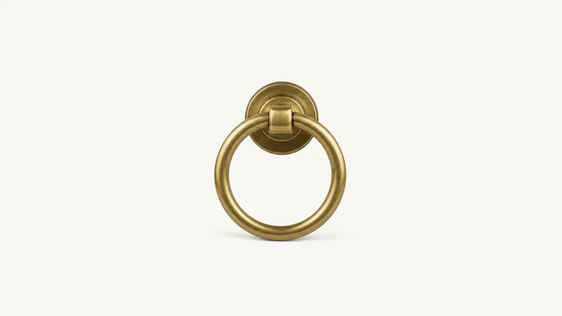 Isolated a brass door knocker in the shape of a ring centred on a seamless pale off-white studio background, generous empty margin on every side for overlaid branding
