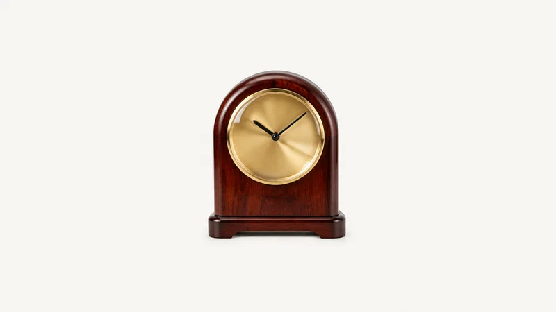 Isolated a mahogany desk clock with a brass face and no numerals centred on a seamless pale off-white studio background, generous empty margin on every side for overlaid branding