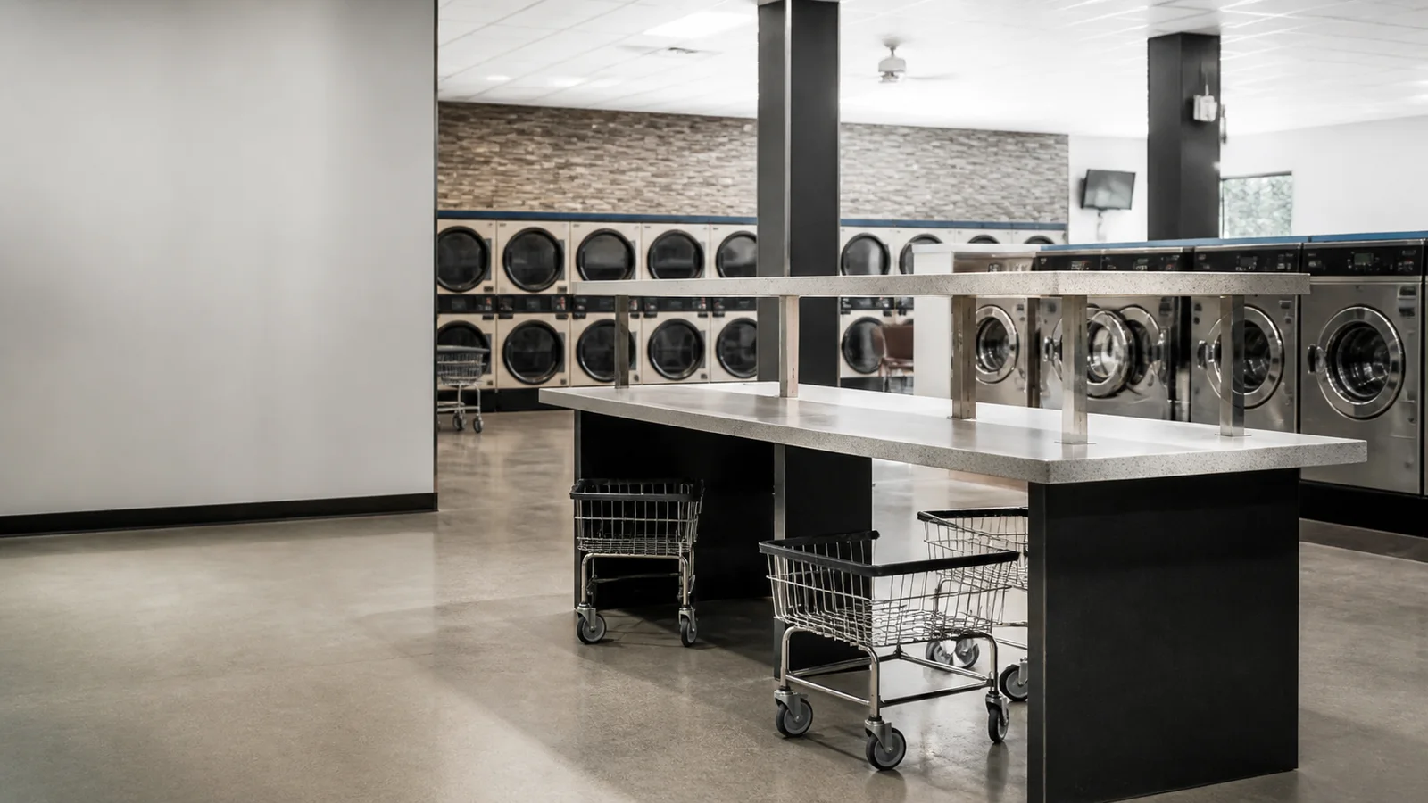 Wide interior view of a folding counter with laundry carts with no people, soft even indoor light, clean uncluttered foreground for text