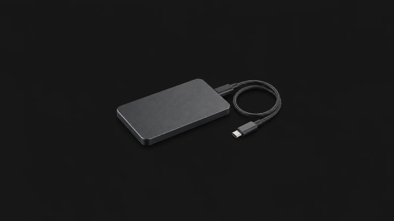 Isolated an external solid-state drive with a braided cable centred on a seamless deep charcoal near-black studio background, generous empty margin on every side for overlaid branding
