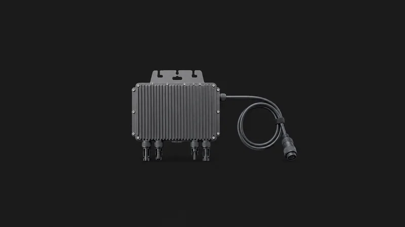 Isolated a microinverter module with its trunk cable centred on a seamless deep charcoal near-black studio background, generous empty margin on every side for overlaid branding