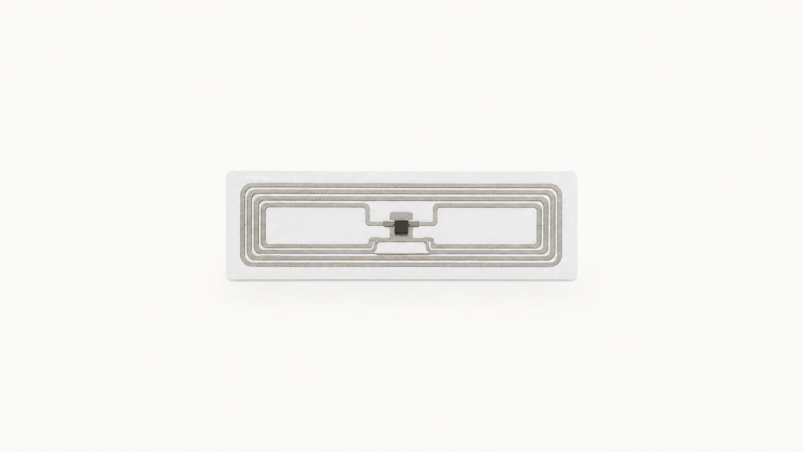 Isolated a passive rfid tag inlay on a blank rectangular label centred on a seamless pale off-white studio background, generous empty margin on every side for overlaid branding