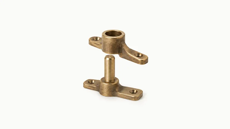 Isolated a cast-bronze rudder pintle and gudgeon pair centred on a seamless pale off-white studio background, generous empty margin on every side for overlaid branding