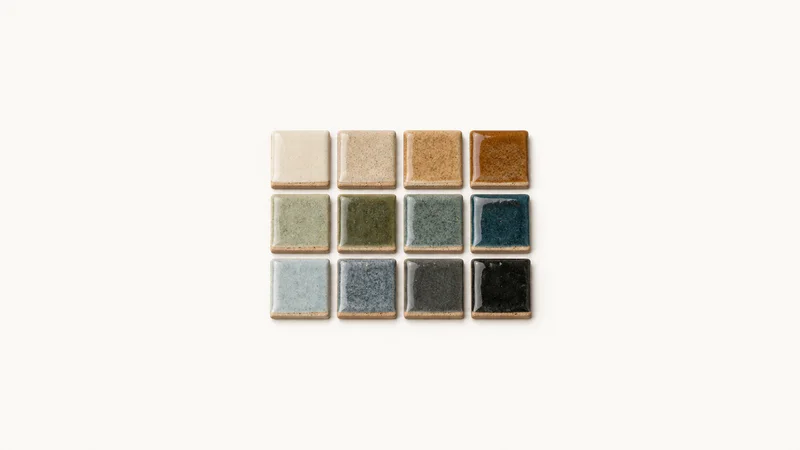 Isolated a set of glaze test tiles in graduated colours centred on a seamless pale off-white studio background, generous empty margin on every side for overlaid branding